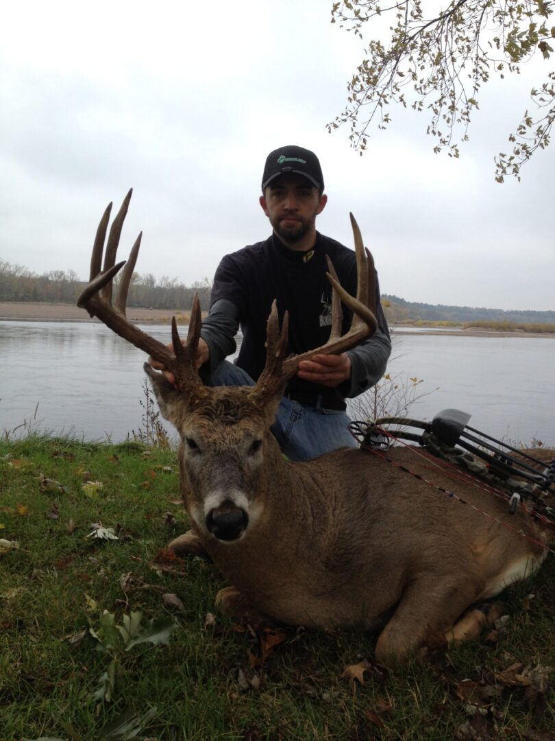 A man holding a dead deer by the antlers