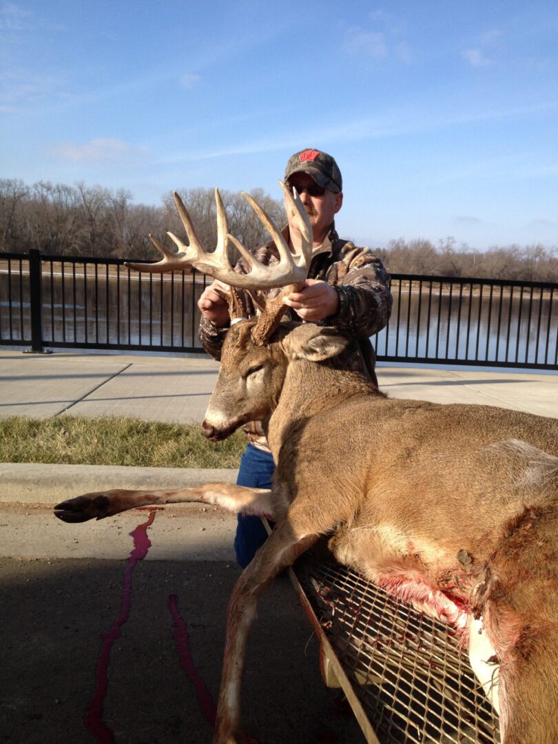 A man holding a dead deer by the antlers