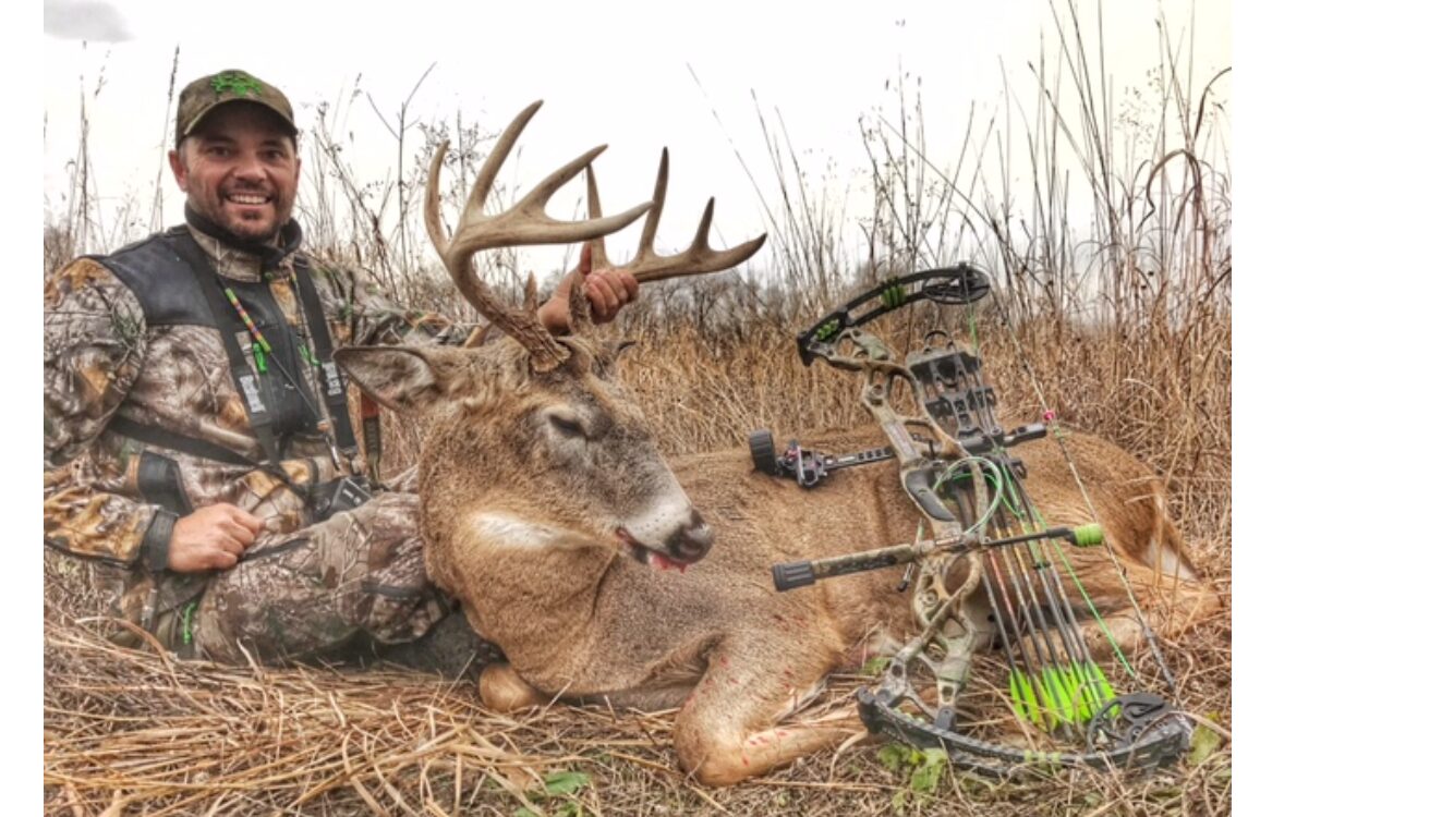 A man with a hunting bow with a dead deer